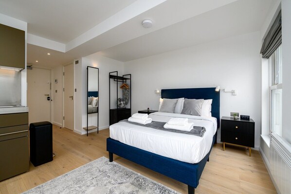 Une chambre à coucher moderne avec un lit, des tables de chevet, une armoire et un miroir.
