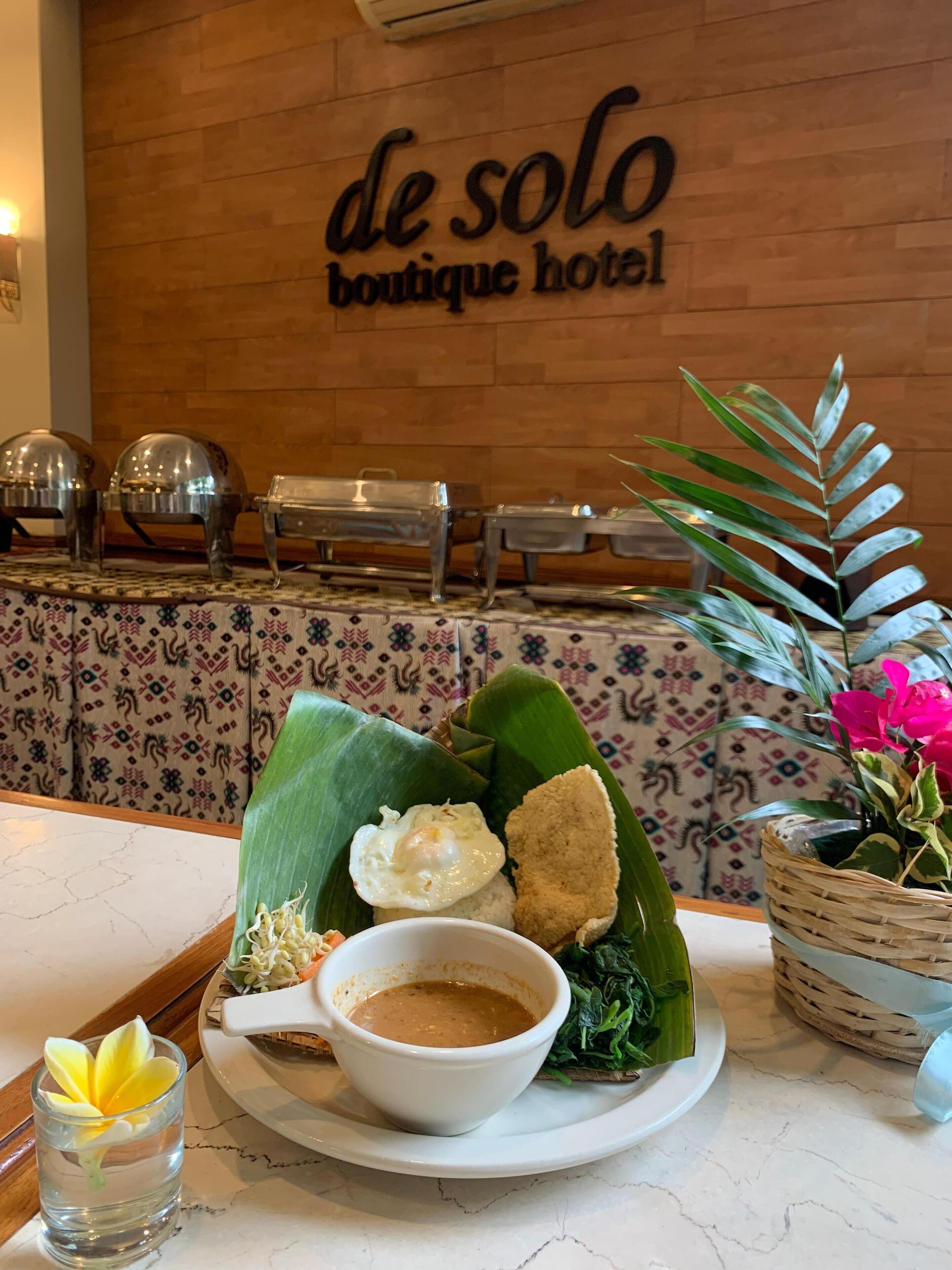 Una mesa con comida, una pared con el letrero 'de solo boutique hotel' y una planta.
