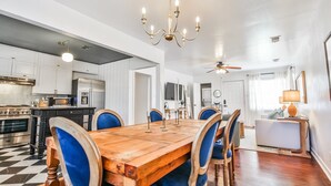 A spacious kitchen with modern appliances, a dining area with a wooden table and blue upholstered chairs, and a ceiling fan. - Cute Bungalow in Central Lubbock (Lubbock)