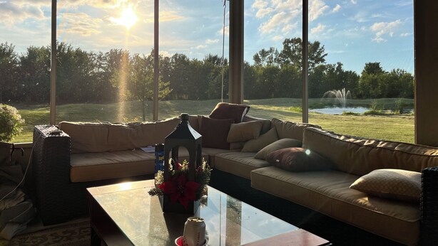 A cozy living room with a large window overlooking a grassy area and a pond.