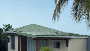 A house with a swimming pool, a patio with chairs, and a palm tree. - L'Échappée Créole (Baie-Mahault)