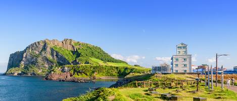Paisaje costero con una isla rocosa destacada y un edificio moderno con una torre.