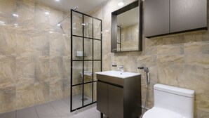 A modern bathroom with a glass-enclosed shower, a vanity with a sink, and a toilet. - Sunrise Castle Pension (Seogwipo)