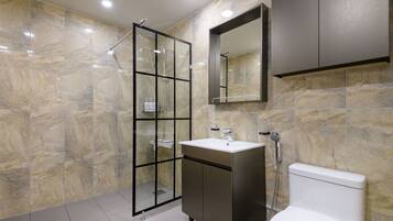 Un baño moderno con ducha de vidrio, tocador con lavamanos y retrete.