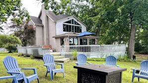 A house with a deck, outdoor seating area with chairs, and a fire pit. - Wolf Lake Haven - Lakefront Sleeps 16 (Jackson)