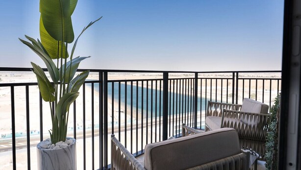 A balcony with a view of the beach, a potted plant, and a seating area. - 1BDR Premium Yas Island - Ferrari, Sea World, F1 (Abu Dhabi)