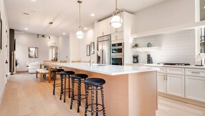 A modern kitchen with a central island, bar stools, and pendant lighting.