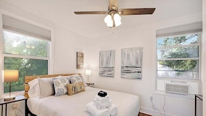 A bedroom with a bed, a ceiling fan, artwork on the walls, and large windows. - Cozy 2BR Getaway in Lake Worth Beach – Walk to the Ocean! (Lake Worth Beach)