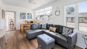 A spacious living room with a large sectional sofa, a dining table with chairs, and a ceiling fan. - Cozy 2BR Getaway in Lake Worth Beach – Walk to the Ocean! (Lake Worth Beach)