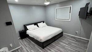 A bedroom with a bed, a ceiling fan, a TV mounted on the wall, and a window with blinds. - Enjoyable 4-bedroom house with AC in vibrant Detroit (Detroit)