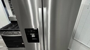 A stainless steel refrigerator in a kitchen with a built-in oven and a wooden floor. - Enjoyable 4-bedroom house with AC in vibrant Detroit (Detroit)