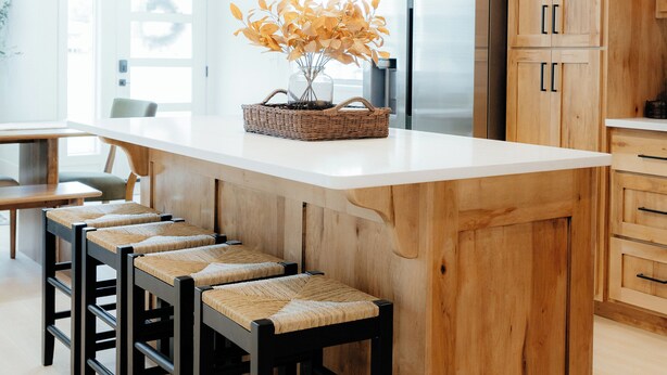Una cocina moderna con armarios de madera, una isla grande con taburetes y un refrigerador.
