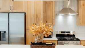 Una cocina con armarios de madera, un refrigerador de acero inoxidable, una estufa y una encimera blanca.