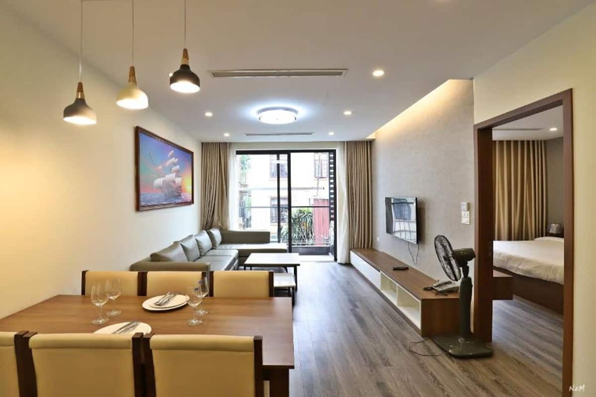 Habitació d'hotel amb zona de menjador, sofà, llit i televisió.