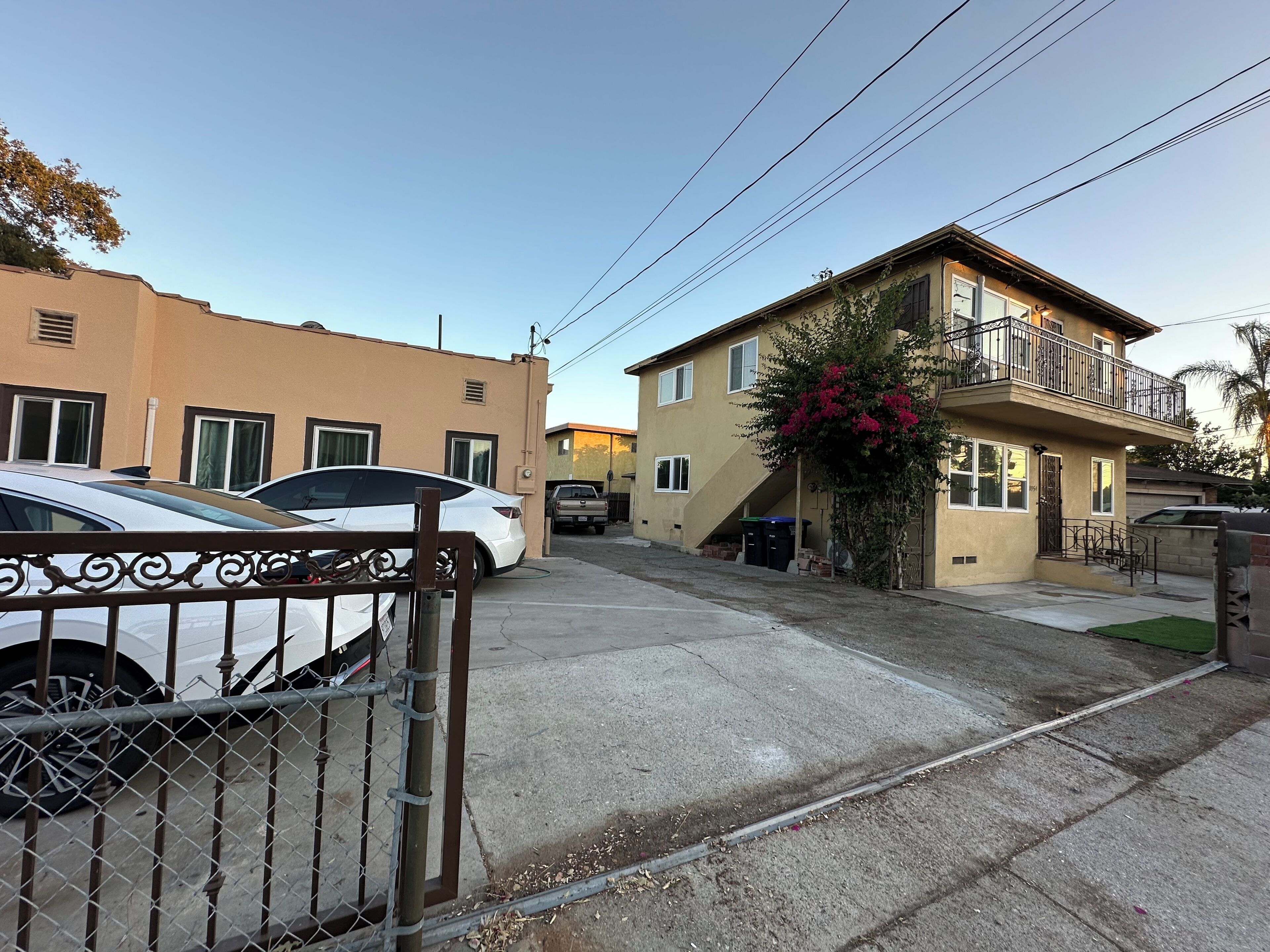 Une rue résidentielle bordée de maisons, avec une allée privée fermée par un portail et des voitures garées.