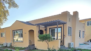 Una casa moderna de dos pisos con fachada color beige, ventanas grandes y un patio cubierto.
