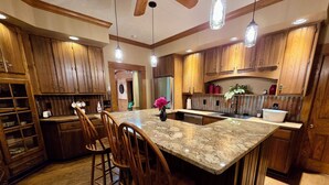 A kitchen with wooden cabinets, a granite countertop, and bar stools.