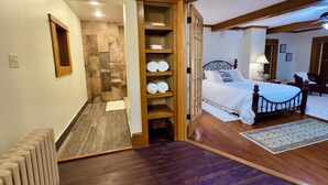 A bedroom with a wooden bed frame, a bedside table with a lamp, and a large window.