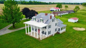 A large two-story house with a porch, surrounded by a well-maintained lawn and a few trees.