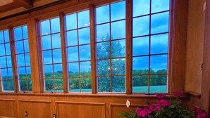 A room with large windows, wooden paneling, and potted plants.