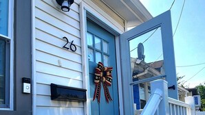 A house with a blue door, white railings, and a number '26' on the wall.
