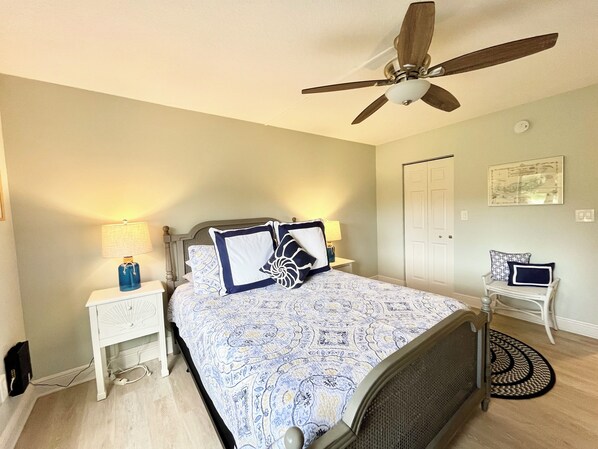 A bedroom with a bed, a ceiling fan, bedside lamps, a nightstand, a desk, and a chair. - BT 3913 Pond View Condo - Welcome to Paradise (Fort Pierce)
