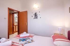 Habitación de hotel con cama, mesita de noche, lámpara, decoración en la pared y puerta que da a un balcón.