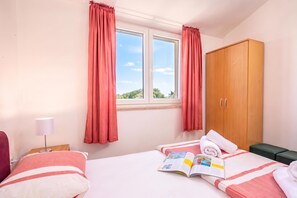 Una habitación de hotel con una cama, una mesita de noche, una lámpara, un armario y una ventana con cortinas.