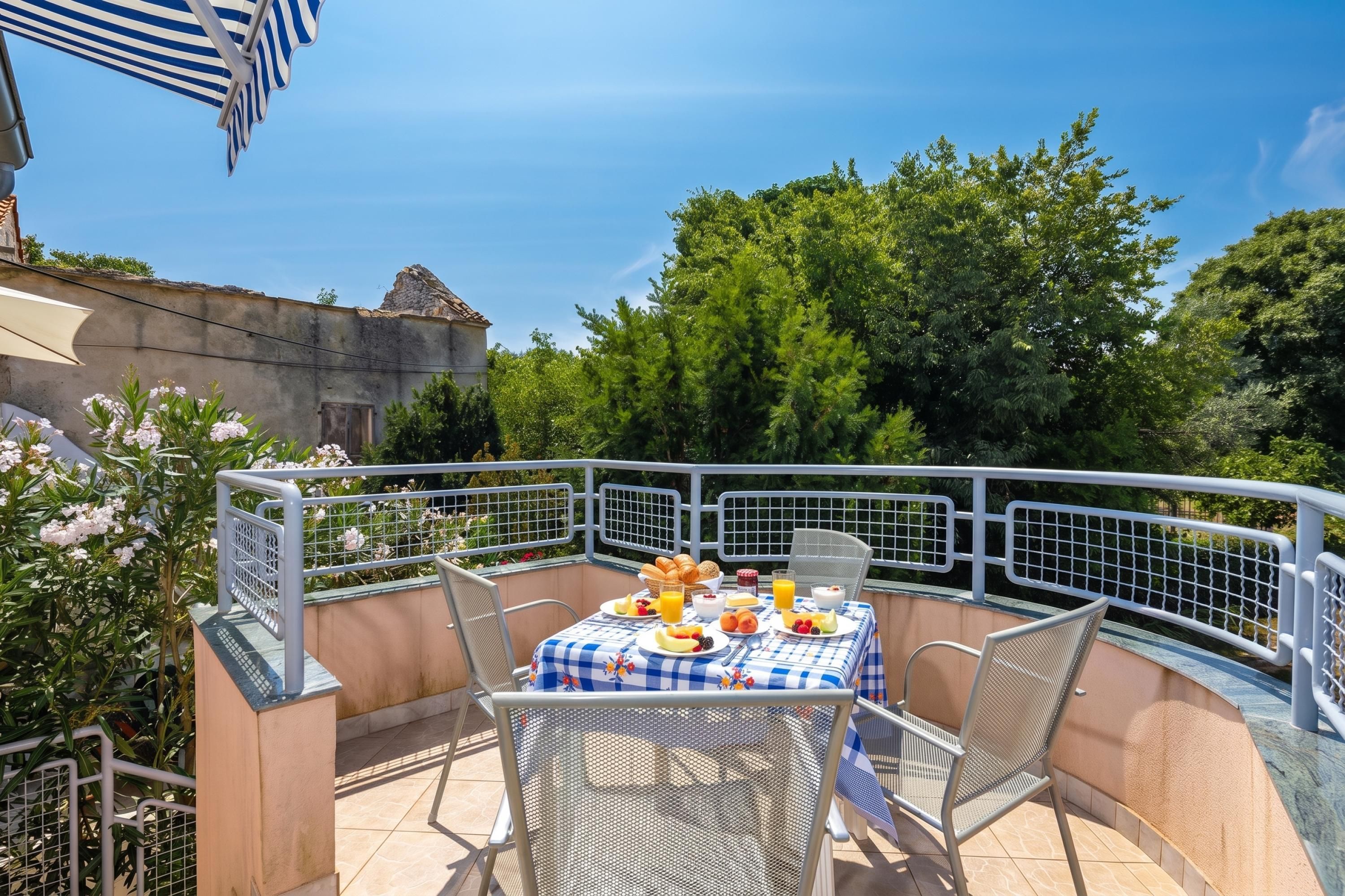 An outdoor dining area with a table set for breakfast, surrounded by metal chairs and a railing.