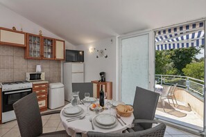 A modern kitchen with a dining area, a TV, and a balcony with a view.