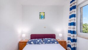 Een slaapkamer met een bed, twee nachtkastjes, een lichtschakelaar aan de muur en een raam met gordijnen.