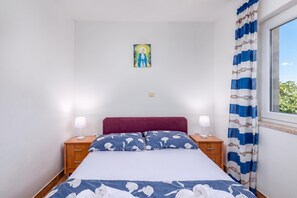 Ein Schlafzimmer mit einem Bett, zwei Nachttischen, einem Wandlichtschalter und einem Fenster mit Vorhängen.