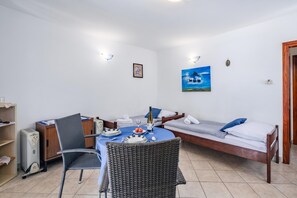 Ein Zimmer mit einem Esstisch für zwei Personen, einem Bett mit gestreifter Bettdecke und einem Gemälde an der Wand.