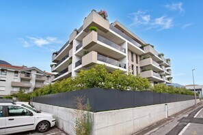 A multi-story residential building with balconies, a concrete retaining wall, and a car parked in front. - Sole E Lago, Riva del Garda, Italy (Riva del Garda)