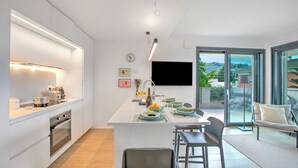 Cozinha moderna com ilha central, forno embutido e área de refeições com banquetas.