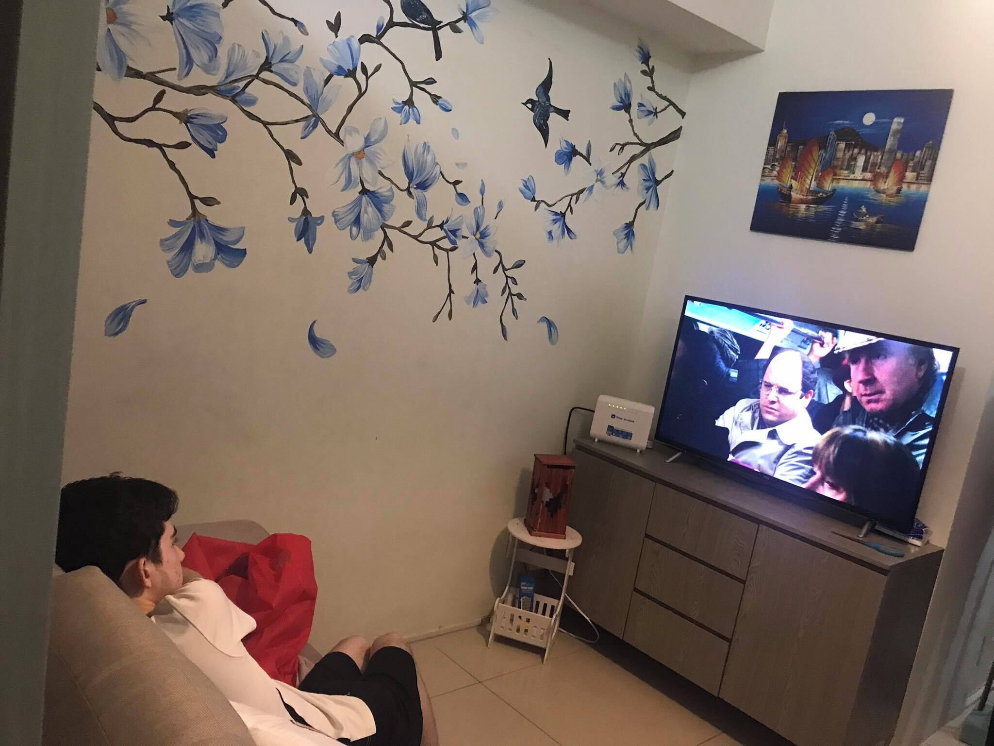 Ein Wohnzimmer mit Flachbildfernseher, einer Couch und einer Wand mit floralen Aufklebern.