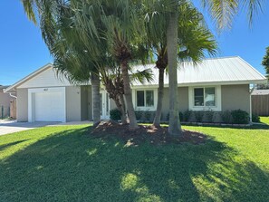 A single-story house with a garage, palm trees, and a well-maintained lawn. - Jupiter Heated Pool/Spa Luxury Home with Private Oasis (Jupiter)
