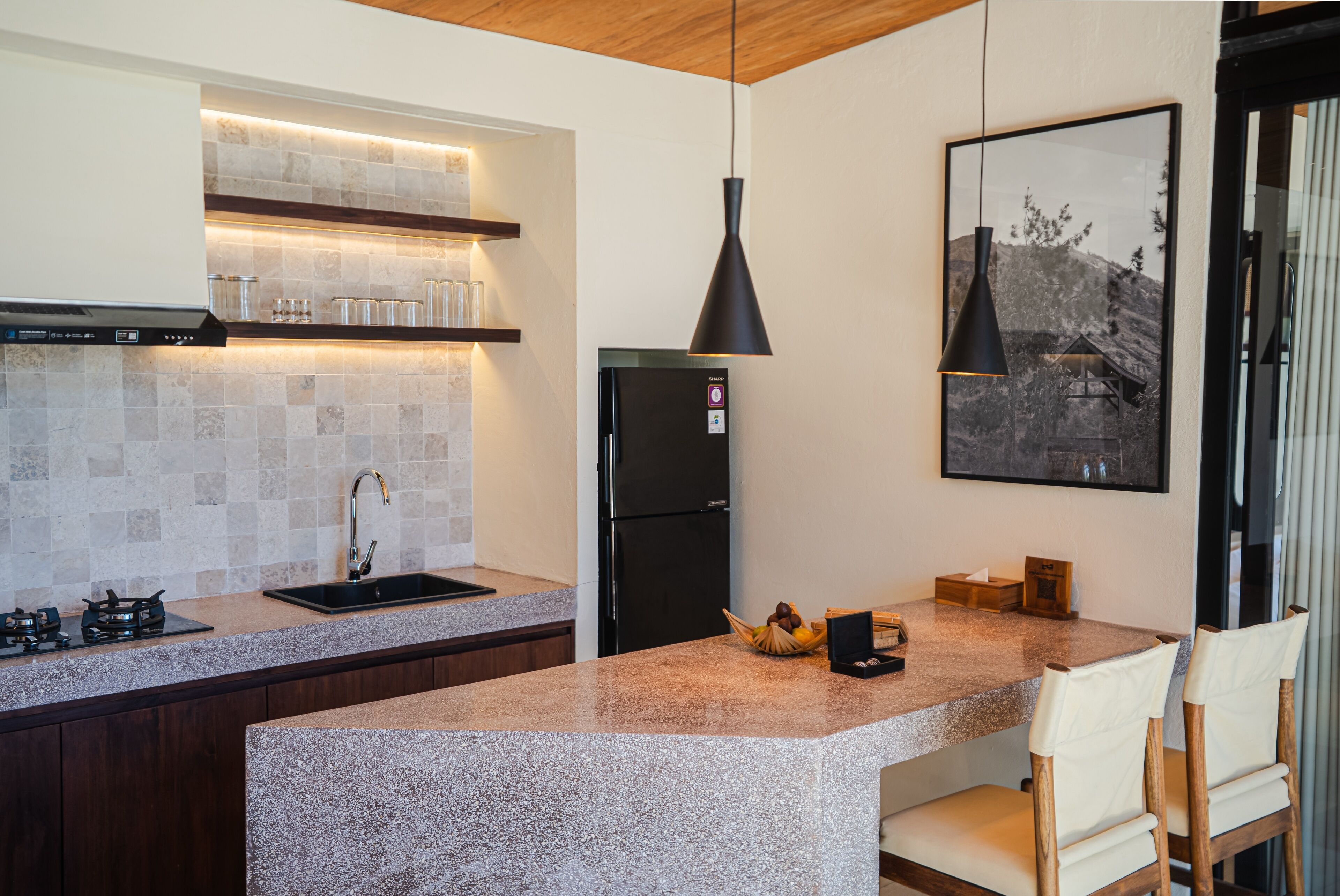 A modern kitchen with a granite countertop, stainless steel appliances, and a pendant light.