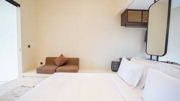 A modern hotel room with a large bed, a sofa, a small seating area, and a mirror.