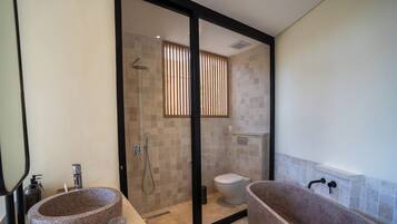 A bathroom with two freestanding stone sinks, a glass-enclosed shower, and a bathtub.
