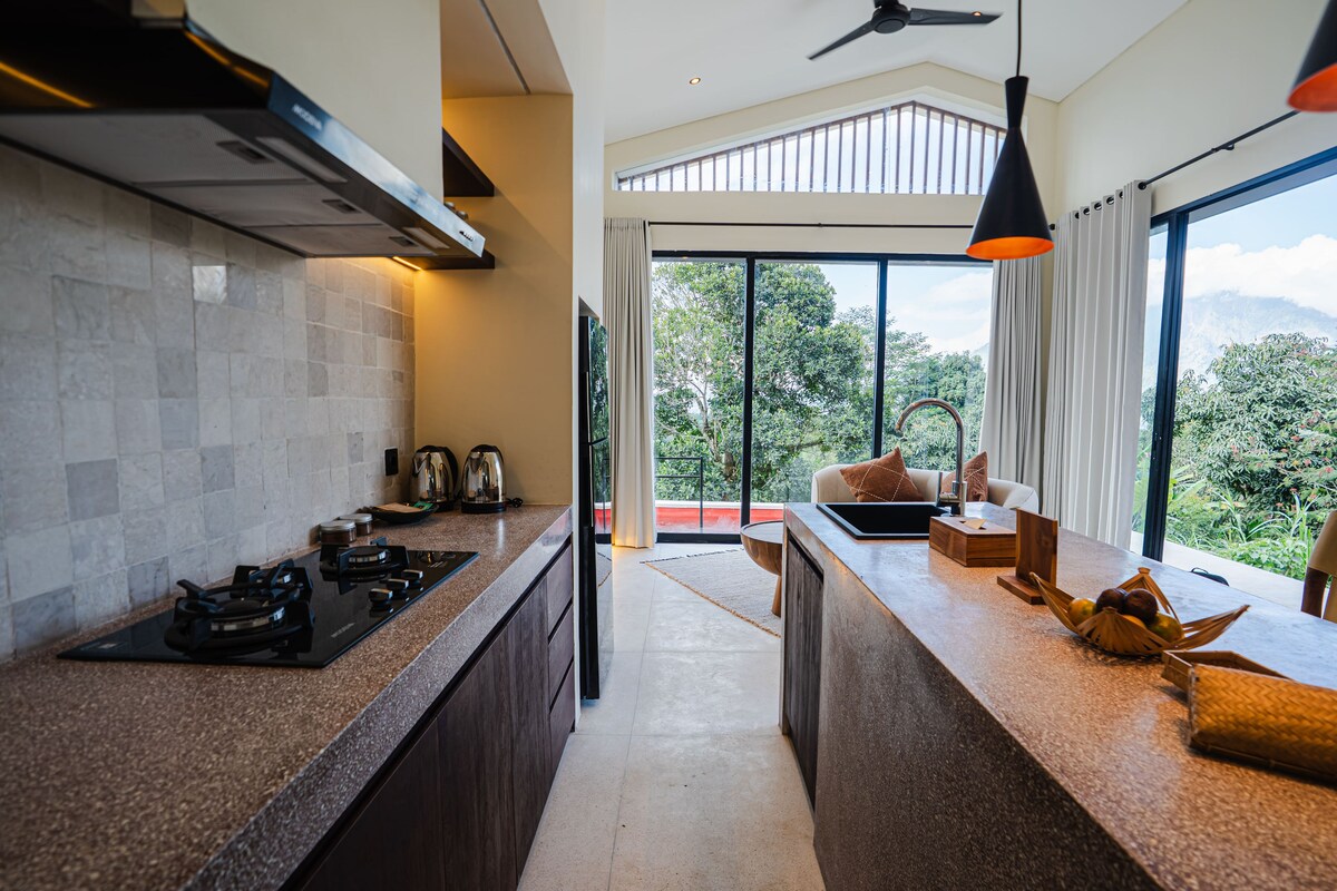 A modern kitchen with a gas stove, a coffee maker, and a view of the outdoors through large windows.