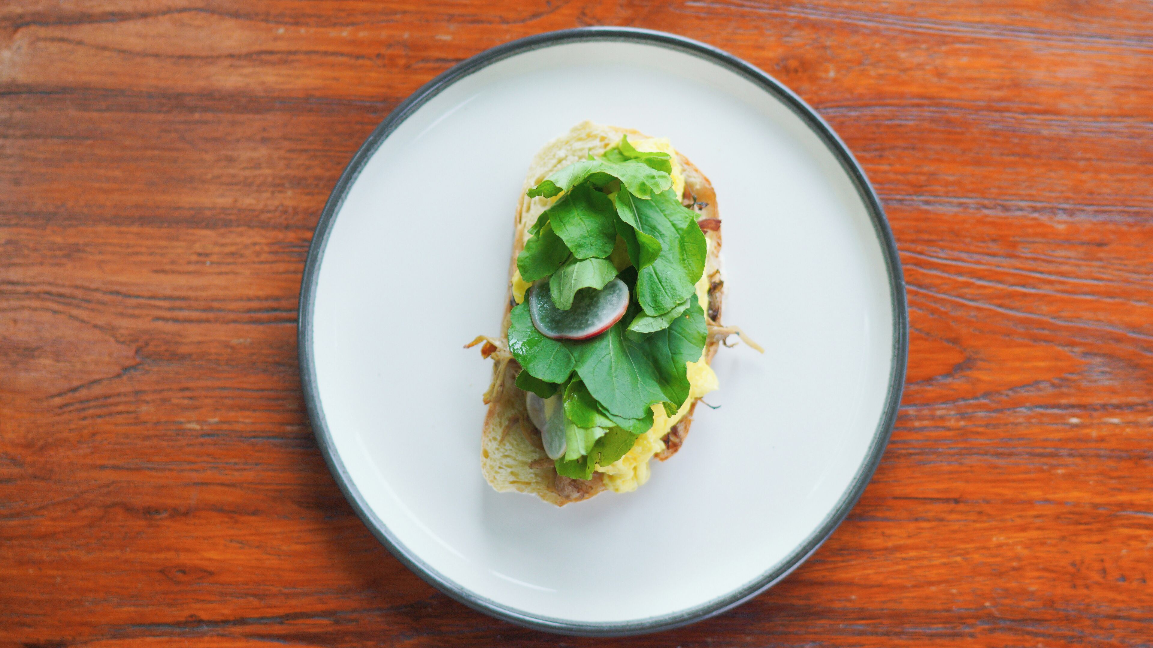 A plate with a sandwich on a wooden table.