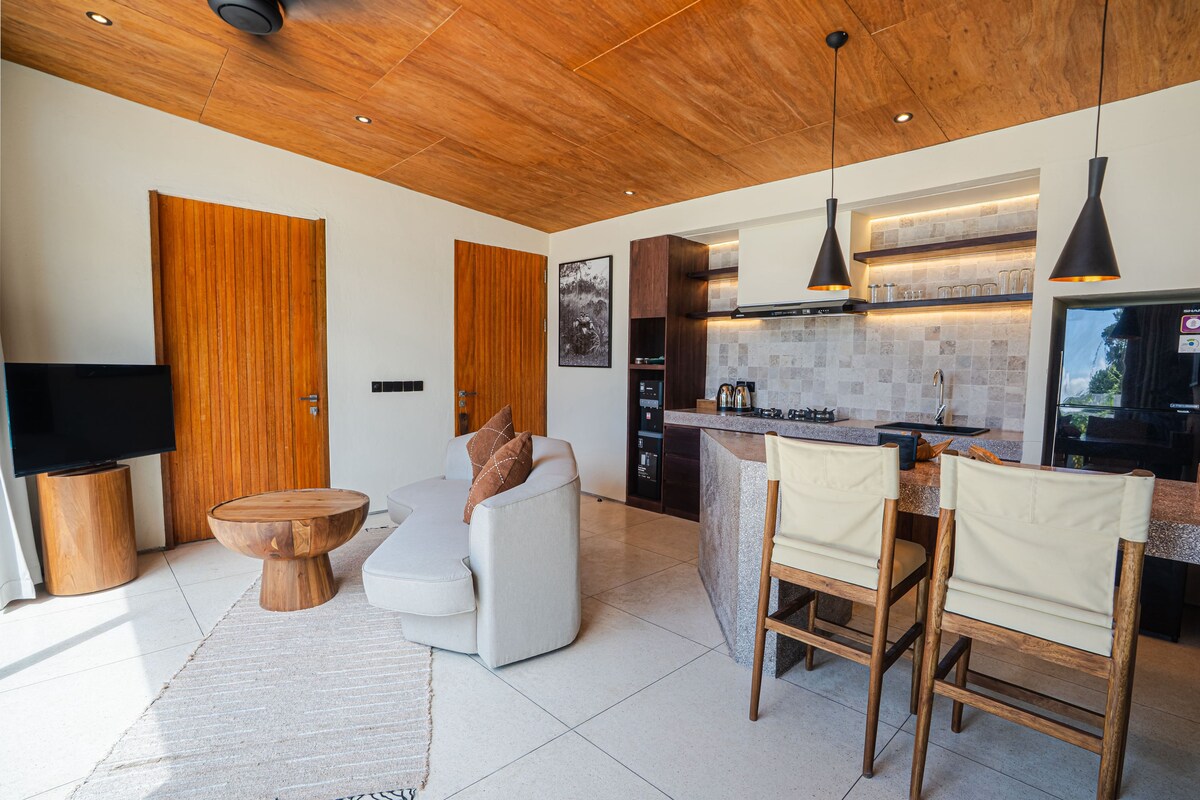 A modern kitchen with wooden cabinetry, a built-in island, and pendant lighting.