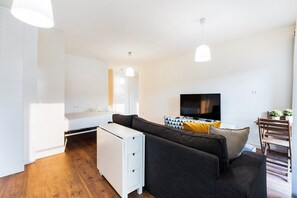 A modern living room with a sofa, a TV, and a dining area. - GuestReady - Peaceful ambience near the ocean (Lavra)