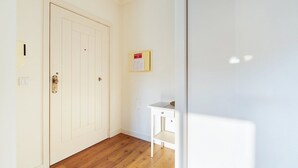 Un passadís amb una porta blanca, una taula petita blanca i un tabló d'anuncis a la paret.