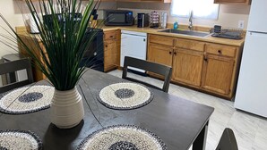 Une cuisine moderne avec des meubles en bois, un four à micro-ondes, un lave-vaisselle et une table à manger avec des sets de table.