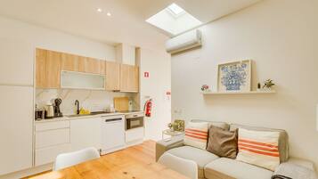 A compact kitchen with wooden cabinets, a dining table, and a sofa.