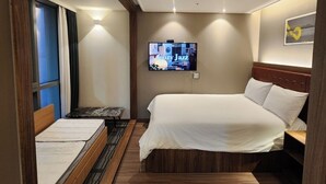 A hotel room with a bed, a desk, a television, and a window with curtains. - Beachfront Famly Hotel - middle Heaundae with cook, 2024 Open (Busan)