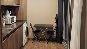 A compact kitchen with a washing machine, microwave, and a small table with chairs. - Beachfront Famly Hotel - middle Heaundae with cook, 2024 Open (Busan)