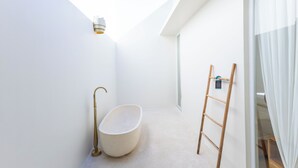 A modern bathroom with a freestanding bathtub, a wooden ladder, and a skylight. - Villa Nokanhui by Pertama Stay (Canggu)